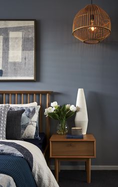 a bed room with a neatly made bed next to a night stand and a painting on the wall