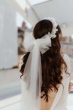 the back of a woman's head wearing a white veil and flower in her hair