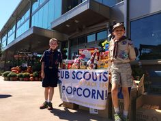 two young boys standing next to a sign that says cub scouts are back in popcorn