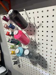 several spools of thread are hanging on a pegboard