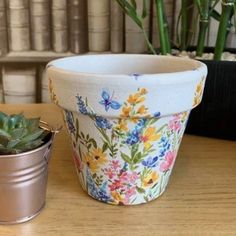 two potted plants sitting on top of a wooden table next to a planter