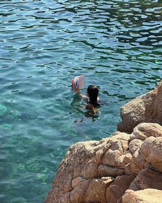 a person swimming in the water near some rocks