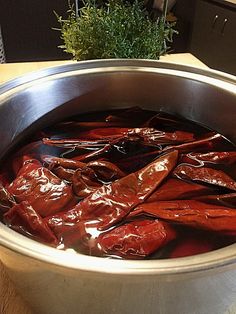 a pot filled with red peppers sitting on top of a wooden table