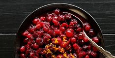 a bowl filled with cranberry sauce on top of a wooden table next to a spoon