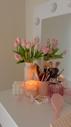 a vase filled with pink tulips sitting on top of a white table next to a mirror