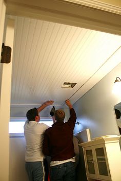 two men are painting the ceiling in their home