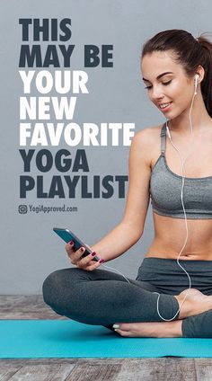 a woman sitting in a yoga pose with headphones on her ears and looking at her phone