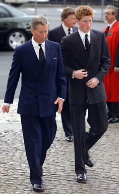 two men in suits are walking down the street with one man wearing a suit and tie