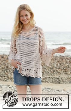 a woman standing on top of a beach next to the ocean with her arms out