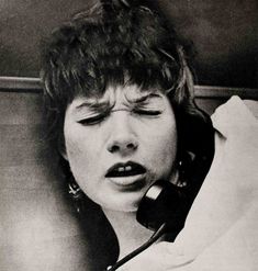 black and white photograph of a woman with her eyes closed while talking on the phone