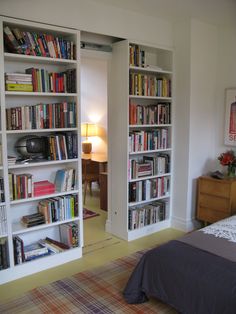 a bed sitting in a bedroom next to a book shelf filled with lots of books