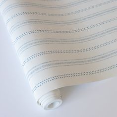 a white and blue striped wallpaper with small dots on the top half of it