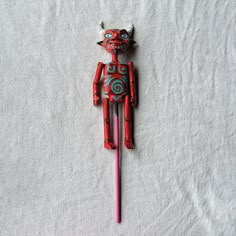 a red and blue toy sitting on top of a white sheet next to a pink pen