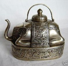 an antique silver tea kettle with ornate designs