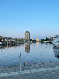 a body of water with boats in it and buildings on the other side, near a dock