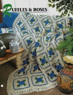 there is a crocheted afghan on the floor next to a potted plant