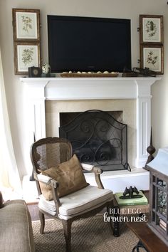 a living room with a fireplace, chair and television on top of the mantel