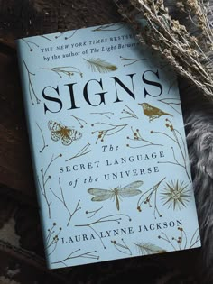 a book sitting on top of a wooden table next to dried flowers and plants in front of it