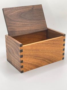 a wooden box with two compartments on the front and one in the middle, sitting on a white surface