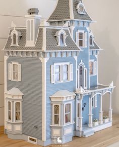 a blue doll house sitting on top of a wooden table