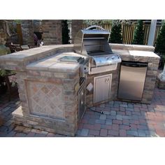 an outdoor kitchen with grill and sink in the middle of brick paversed patio