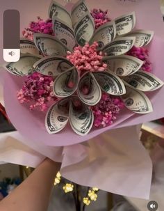 a bunch of money sitting on top of a pink paper bouquet with flowers in it