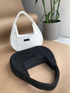 a white handbag sitting on top of a table next to a potted plant