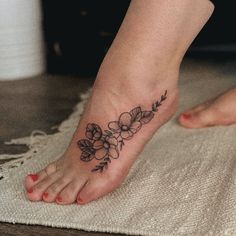 a close up of a person's foot with a flower tattoo on the toe