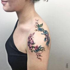 a woman's shoulder with flowers on it and leaves in the middle of her arm