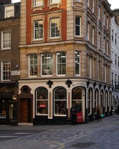 an old building with many windows and people walking on the sidewalk