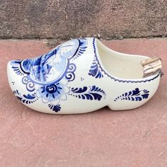 a blue and white shoe sitting on the ground next to a brick wall in front of a building