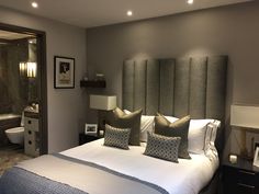 a bedroom with a large bed and grey headboard