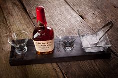 a bottle of maker's mark on a wooden tray with two glasses next to it