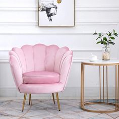 two pink chairs sitting next to each other near a table with a vase on it