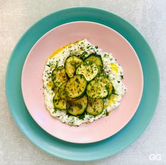 a pink plate topped with cucumbers and cream cheese on top of a white table