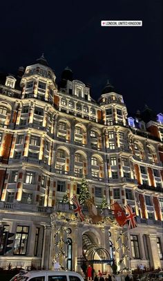 a large building with christmas lights on it's side and cars parked in front