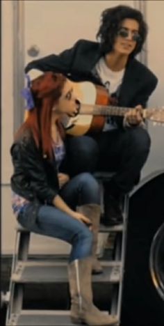 a woman sitting on top of a chair next to a man with an acoustic guitar