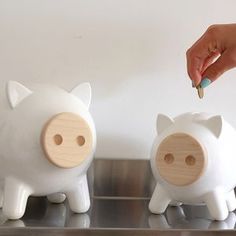 two white piggy banks sitting on top of a metal counter