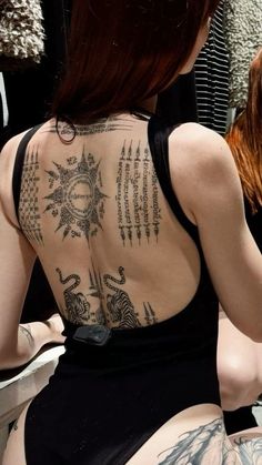 a woman with tattoos on her back sitting down