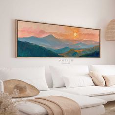 a painting hanging on the wall above a couch in a room with white furniture and pillows