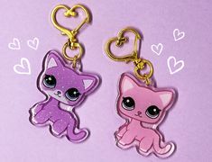 two key chains with little kittens on them, one is pink and the other is purple