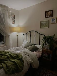 a bed with white sheets and green blankets on top of it next to a window