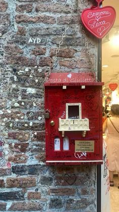 a red mailbox on the side of a brick building with graffiti written all over it