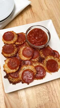 a white plate topped with mini pizzas next to a bowl of ketchup