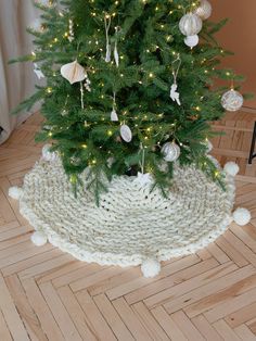 a small christmas tree in a knitted basket on the floor with lights around it