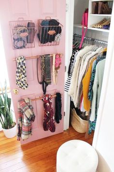 a closet filled with lots of clothes next to a white chair and potted plant