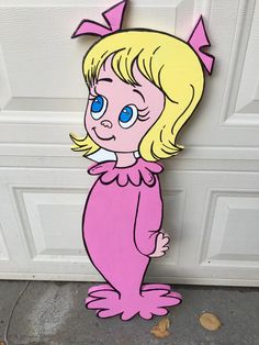 a wooden cutout of a cartoon character with blue eyes and blonde hair standing in front of a garage door