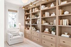 a white chair sitting in front of a book shelf filled with books and vases