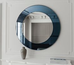 a round mirror on the wall above a fireplace