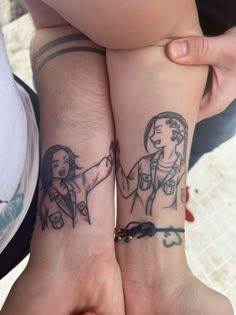 two people holding hands with tattoos on their arms